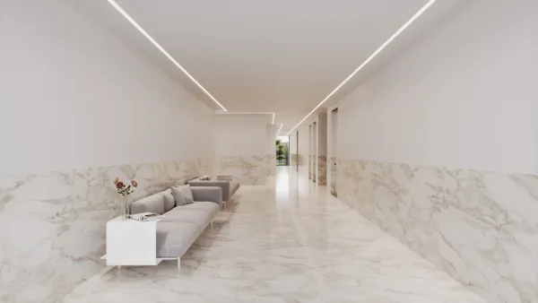 Zona comum interior, com sofá e pavimento em pedra clara